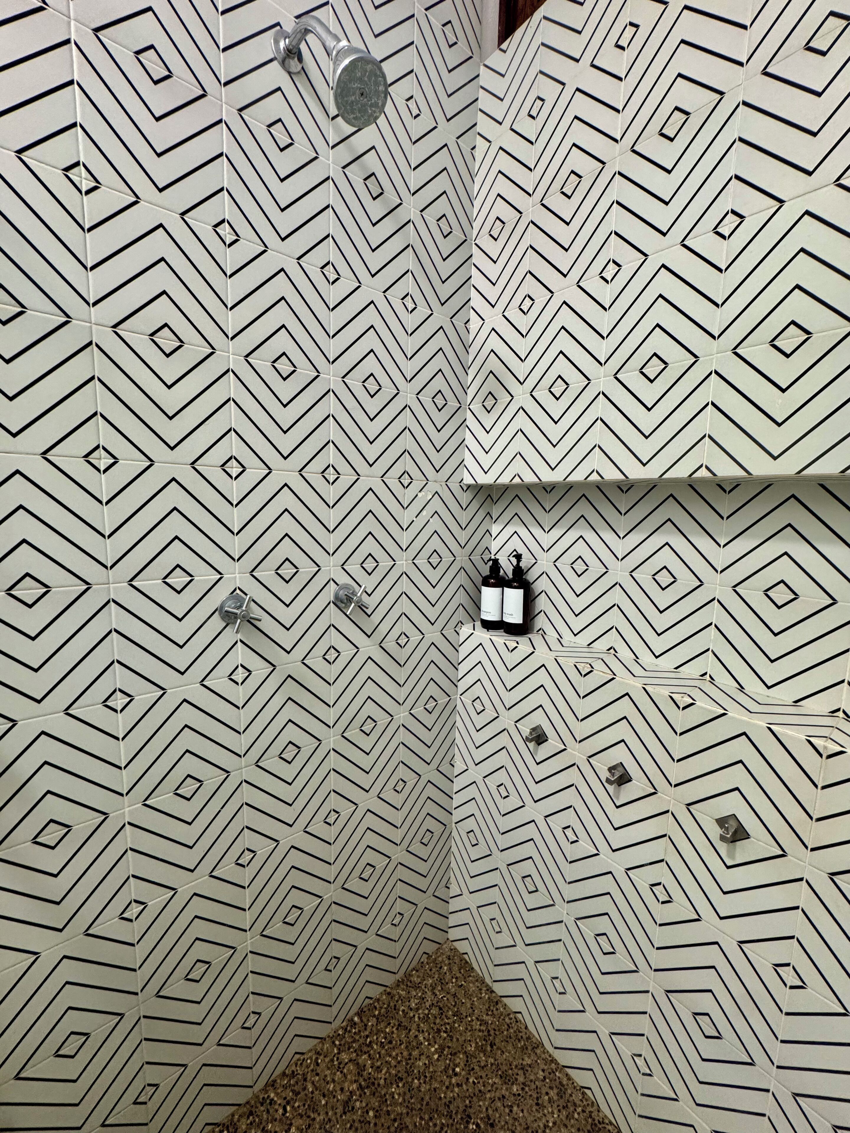 A bathroom with a geometric patterned tile design, a shower area, and a toilet.