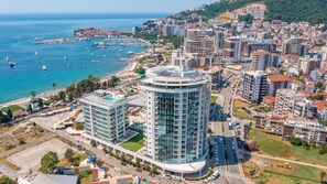 Un hôtel de grande hauteur à la façade moderne en verre, situé près d’une zone côtière dotée d’un port de plaisance.