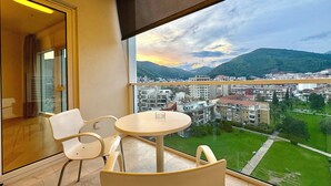 Ein Balkon mit Tisch und Stühlen, der Blick auf eine Stadtlandschaft und Berge bietet.
