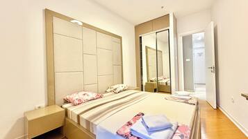 A bedroom with a bed, a nightstand, a mirror, and a door.