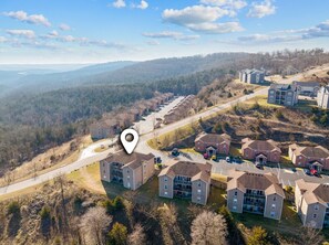 Vue aérienne d’un quartier résidentiel comprenant de nombreux immeubles d’appartements, des routes et, au loin, un paysage vallonné.
