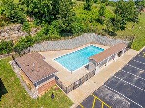 Une piscine rectangulaire dotée d’une plage carrelée, entourée d’un mur de briques et d’un espace couvert avec un toit.