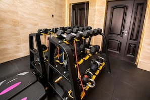 A gym with weightlifting equipment, a black exercise bench, and a door in the background. - Grand Bohabs (Abuja)