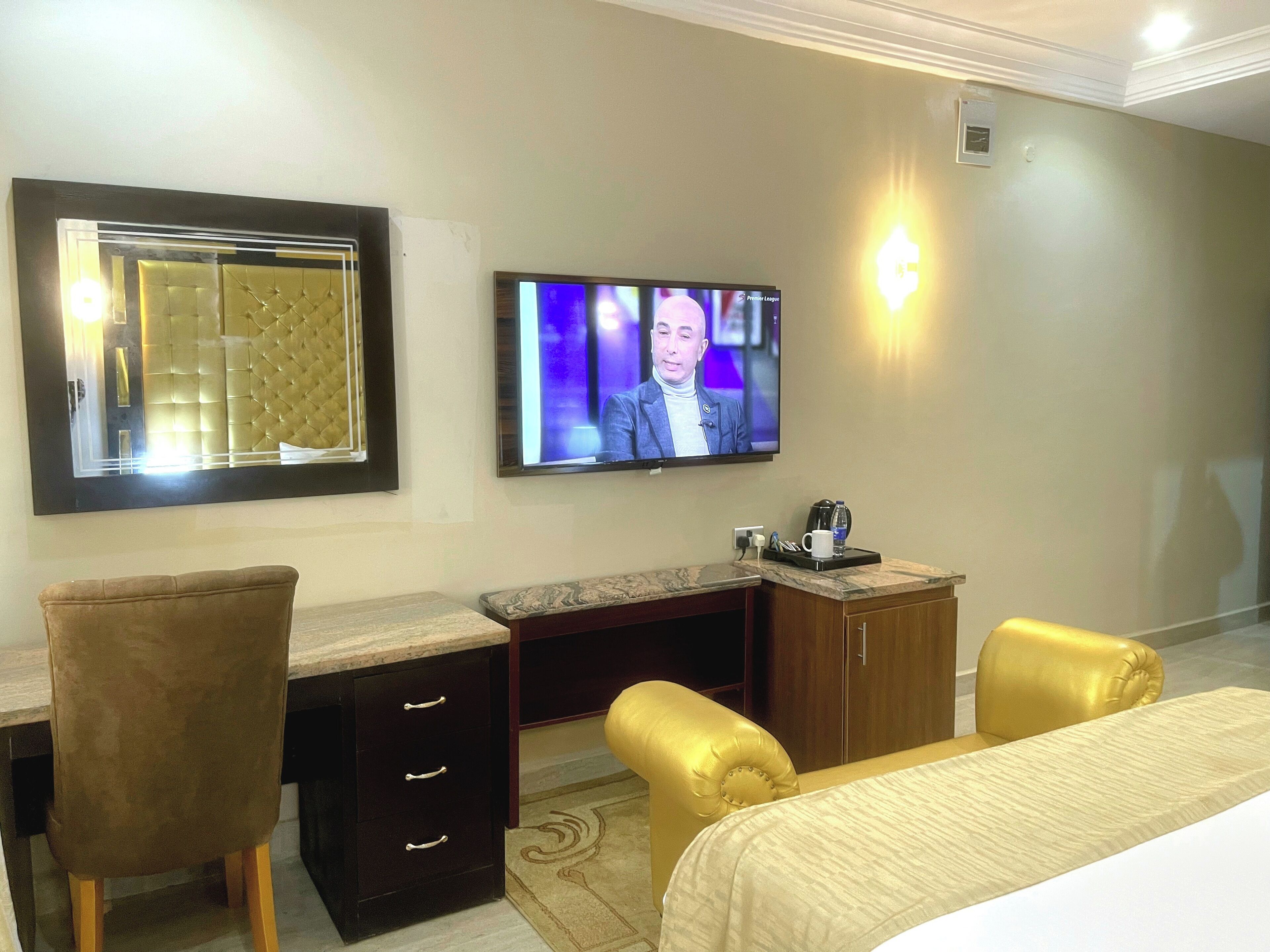 Une chambre d’hôtel avec un grand lit, un bureau avec des tiroirs, une chaise, un téléviseur fixé au mur et un petit placard.