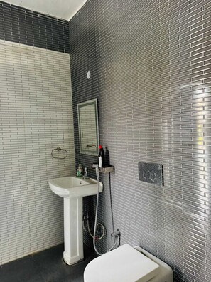 A bathroom with a white sink, a toilet, and a shower area. - Royal green farm stay  (Sohna)