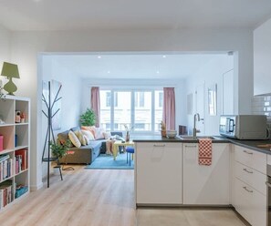 A modern apartment with a kitchen, dining area, and living room.