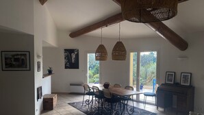 A spacious dining area with a large table, chairs, and hanging wicker lamps. - 140 M2 architect-designed house in a quiet cul-de-sac. (Vaison la romaine)