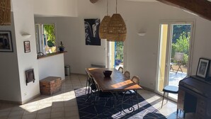 A spacious living area with a wooden dining table, a sofa, and a large window providing natural light. - 140 M2 architect-designed house in a quiet cul-de-sac. (Vaison la romaine)