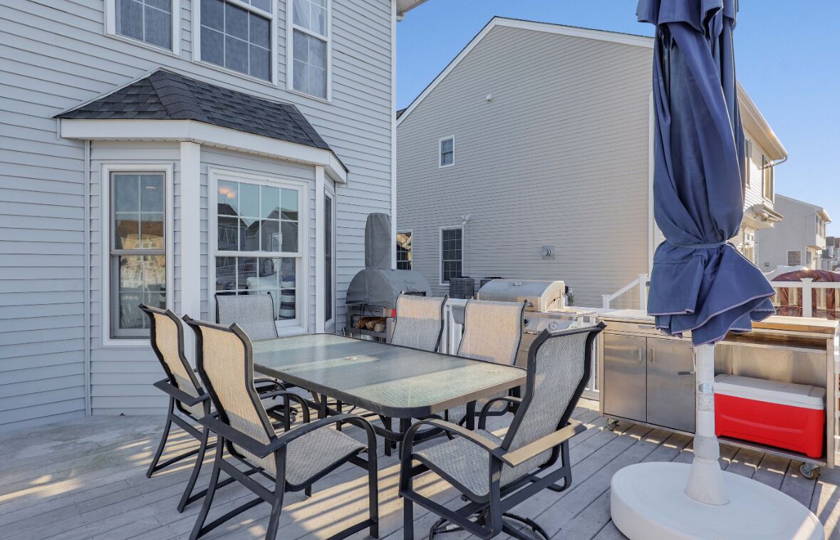 A deck with a table and chairs, a grill, and a red cooler.
