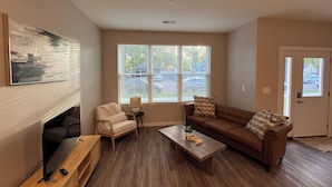 A living room with a flat-screen TV, a sofa, a chair, a coffee table, and a fireplace. - SPNC Unit 101 (Fargo)