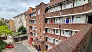 Un edificio residencial de varios pisos con fachada de ladrillo, varios balcones y un estacionamiento al frente.