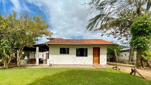 Una casa de un piso con techo de tejas, un porche delantero y un césped bien cuidado.