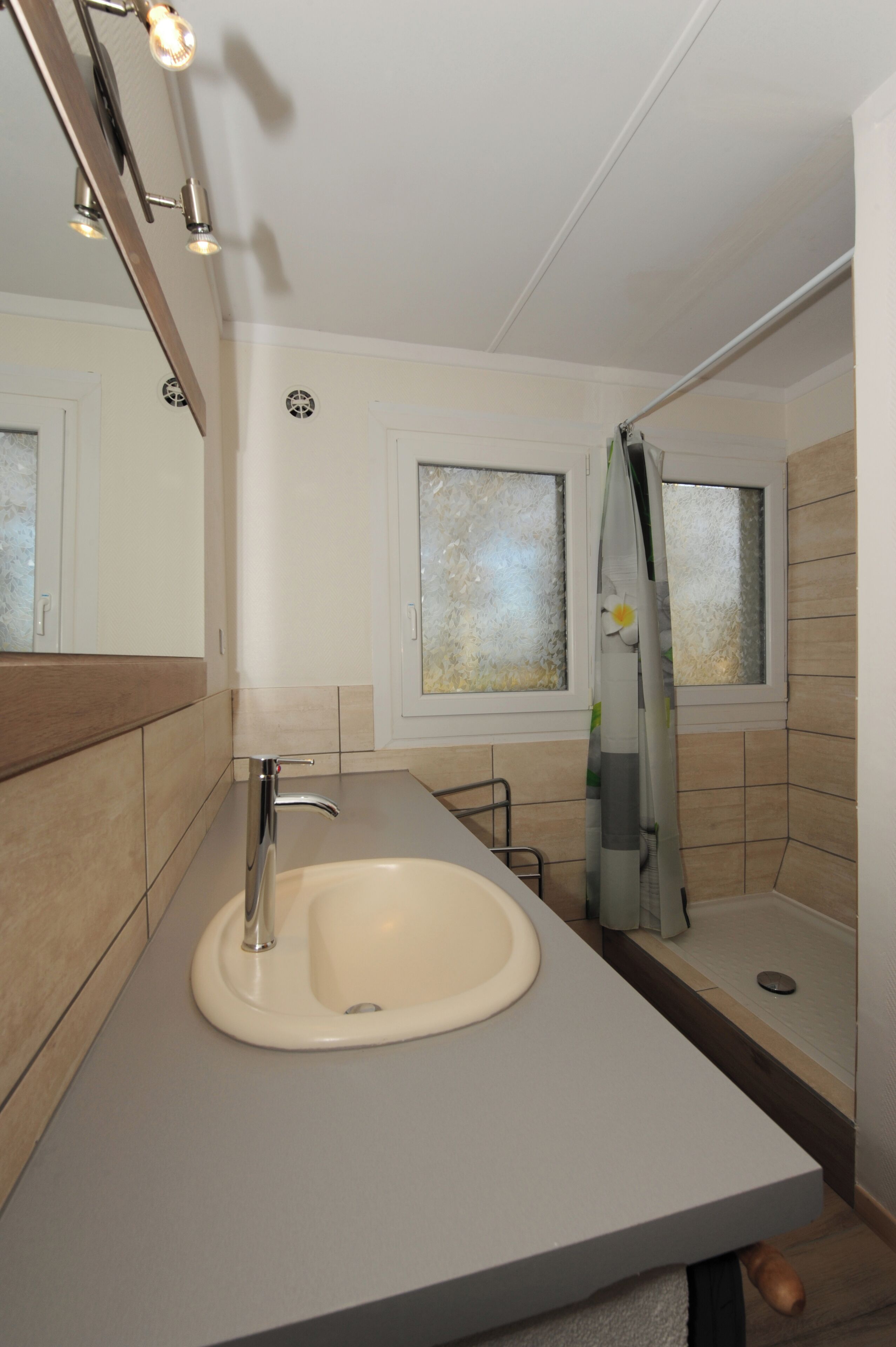 Ein modernes Badezimmer mit Waschbecken, Spiegel und Dusche.