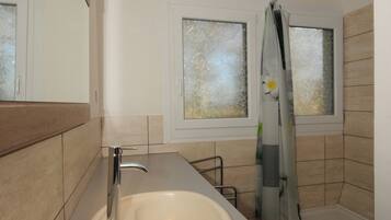 Ein modernes Badezimmer mit Waschbecken, Spiegel und Dusche.