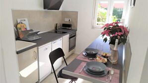 Cozinha compacta equipada com lava-louças, forno e pequena área de jantar com mesa posta para dois.