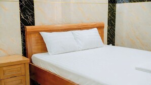 A neatly made bed with white linens in a room with marble-patterned walls. - Thulee Luxury Hotel - Phu My (Ho Chi Minh City)