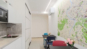 A compact kitchen with a microwave, sink, and a dining area with a table and chairs. A map is displayed on the wall. - Domus Suites (Rome)