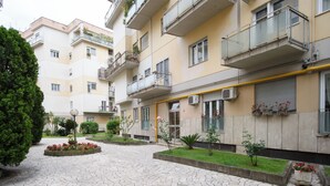 A multi-story residential building with balconies, a paved courtyard, and small gardens. - Domus Suites (Rome)