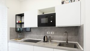 A modern kitchen with a built-in microwave, a kettle, and a sink. - Domus Suites (Rome)