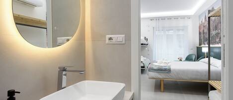 Uma casa de banho moderna com um espelho grande, uma sanita branca e uma tomada elétrica visível.