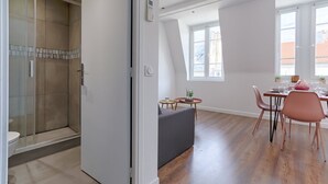 Een modern appartement met een douche, een eethoek met tafel en stoelen, en een bank.