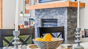 Un comedor con chimenea de piedra, dos velas y un bol de limones sobre la mesa.
