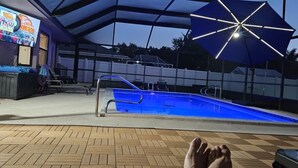 A pool area with a ceiling fan, a poolside umbrella, and a TV screen displaying a show. - Enjoy Pool, Billiards, Sauna, Access to the Lake (Lake Placid)