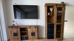 A wooden entertainment center with a flat-screen TV, a coffee table, and a cabinet with glass doors. - "Bergnest", Oberstaufen/Steibis (Oberstaufen)