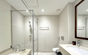 Enjoy a refreshing shower in the glass-enclosed shower with handheld showerhead and wall-mounted control panel.