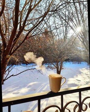 A cup on a balcony railing overlooking a snowy landscape with bare trees and a clear sky. - Sweet Vibe Home (Almaty)