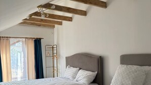 A bedroom with two beds, wooden beams on the ceiling, a window with curtains, and a metal coat rack. - Sweet Vibe Home (Almaty)
