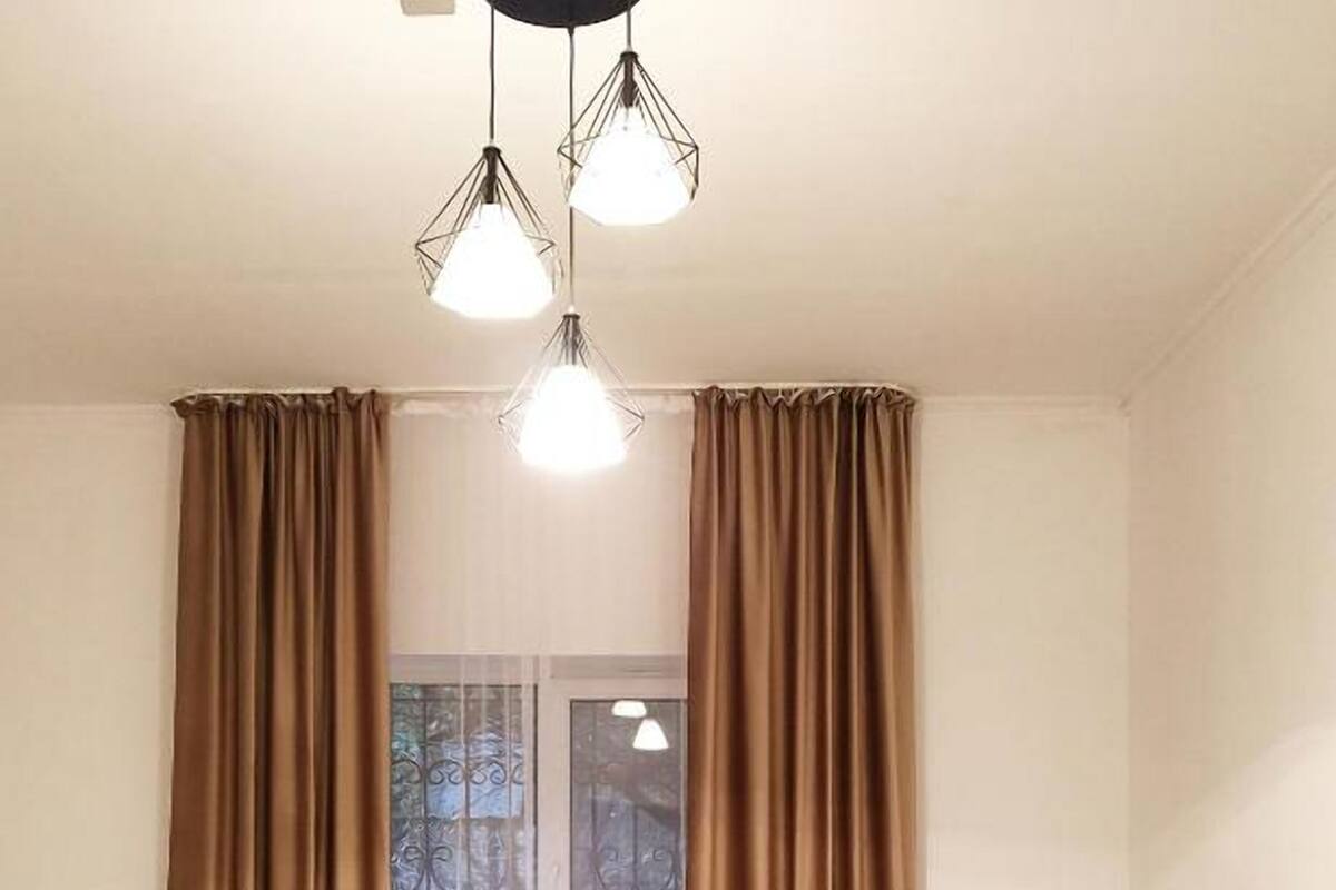 A room with two single beds, a window with curtains, a radiator, and a patterned rug.