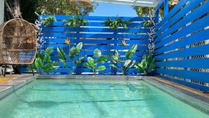 A swimming pool with clear blue water, surrounded by a blue fence with plants and flowers. - Parguera Beach Club Hotel (Lajas)