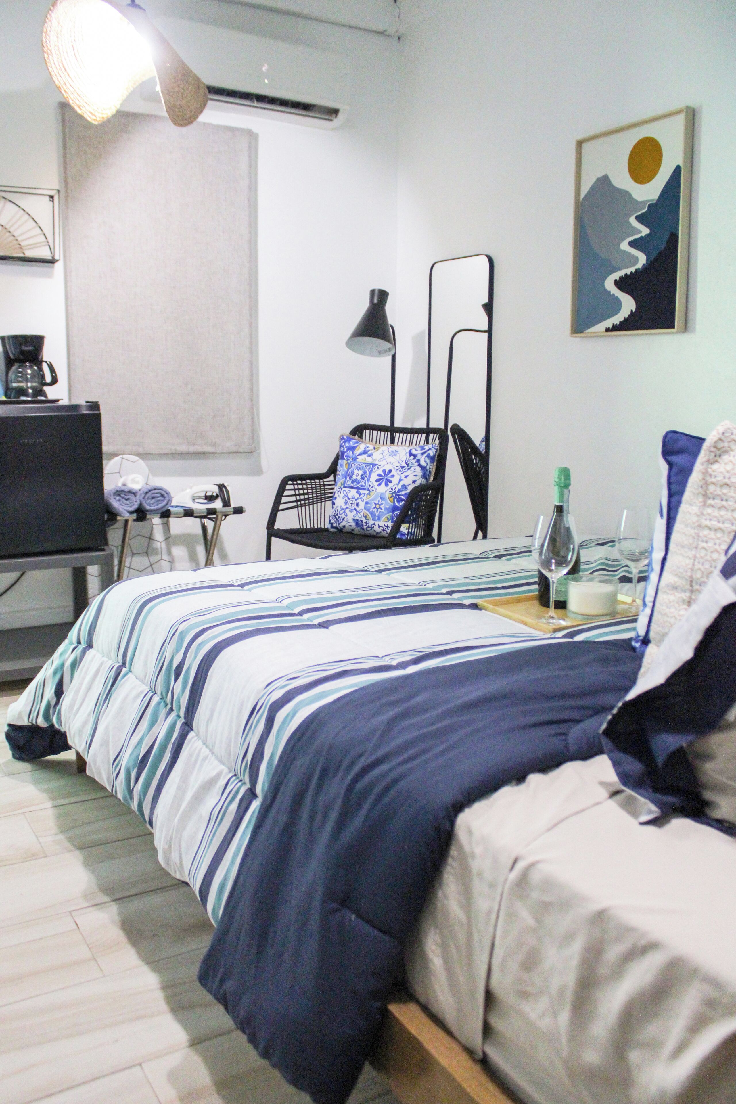 A neatly arranged bedroom with a bed, a chair, a desk, and a television.