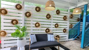 A room with a white wooden slatted wall, a black sofa with patterned cushions, and a staircase with blue railings. - Parguera Beach Club Hotel (Lajas)