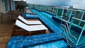 A rooftop pool with blue tiles, lounge chairs, and a white umbrella. - Edificio Promenade II Apt 1108 (Maceio)
