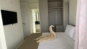 A hotel room with a bed, a TV mounted on the wall, a wardrobe, and a mirror. - Edificio Promenade II Apt 1108 (Maceio)