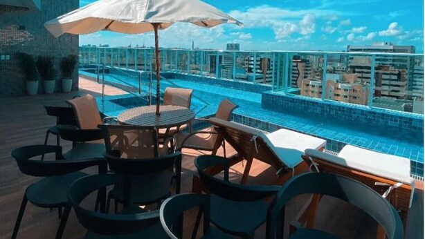 A rooftop pool area with lounge chairs and umbrellas, overlooking a cityscape. - Edificio Promenade II Apt 1108 (Maceio)