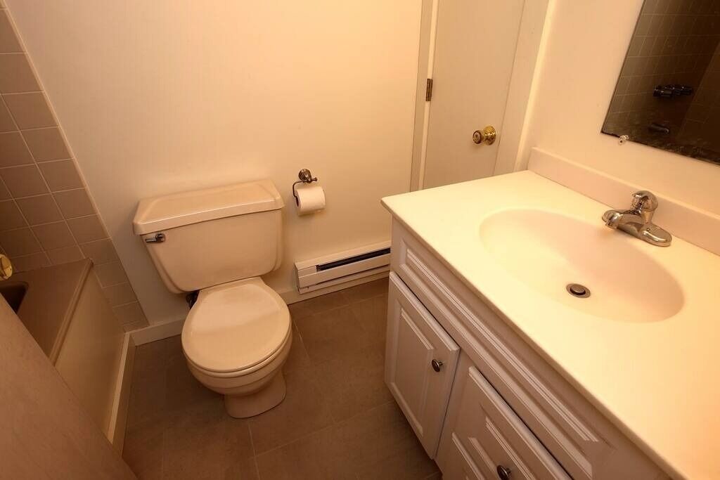 A bathroom with a toilet, sink, and mirror.
