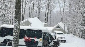 A snow-covered area with a bus parked in front of a building. - 6BR 3BA - MT SNOW, SKIBACK TRAIL, FREE SHUTTLE, POOL, BBQ - Green Mountain House (Dover)