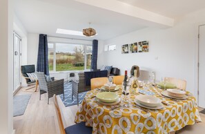 A dining area with a round table set for four, a sofa, and a view of the outdoors.