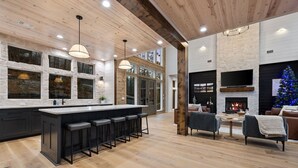 Une cuisine moderne dotée d’un grand îlot central, de tabourets de bar et d’une cheminée dans l’espace salon.