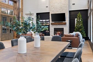 A spacious room with a large wooden table, comfortable seating, a fireplace, and a Christmas tree. - 5BR Luxury Midnight Skies | 4 King Suites & Hot Tub (Broken Bow)