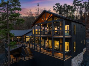 A multi-story cabin with a balcony, wooden deck, and a staircase leading to the upper levels. - 5BR Luxury Midnight Skies | 4 King Suites & Hot Tub (Broken Bow)