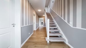 Ein Flur mit einer Holztreppe, grauen Wänden und einem Holzboden.