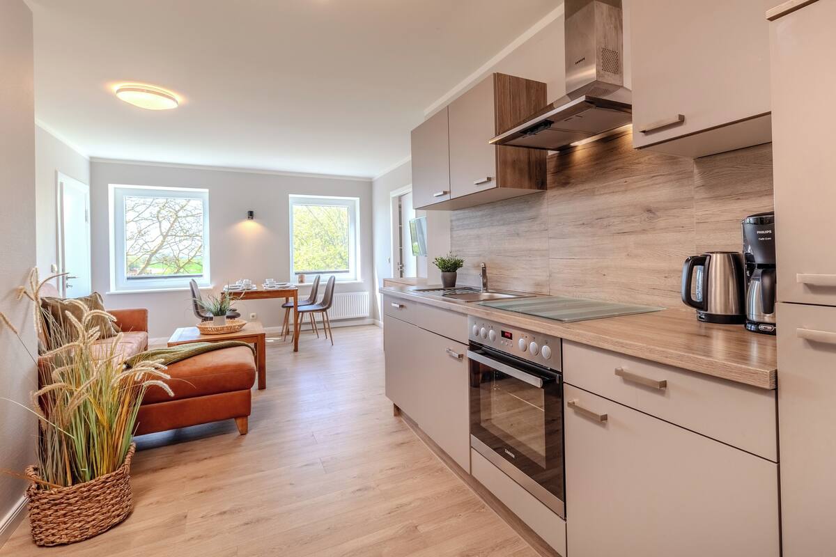 A modern kitchen with a built-in oven, a coffee maker, and a dining area with a table and chairs.