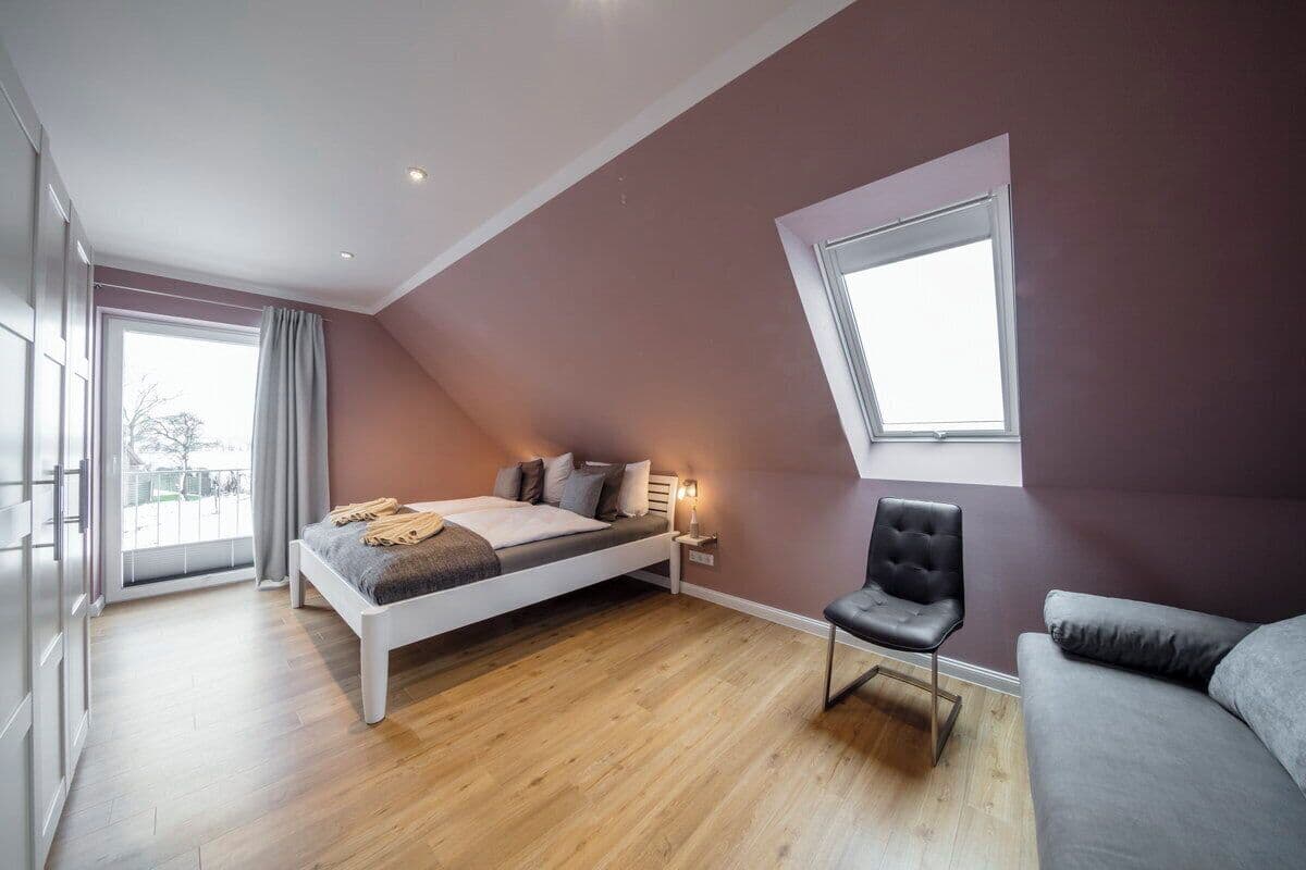 A modern bedroom with a bed, a chair, and a sofa.