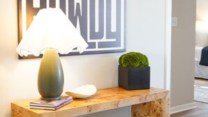 Un bureau en bois, une lampe, une plante en pot et un coussin.