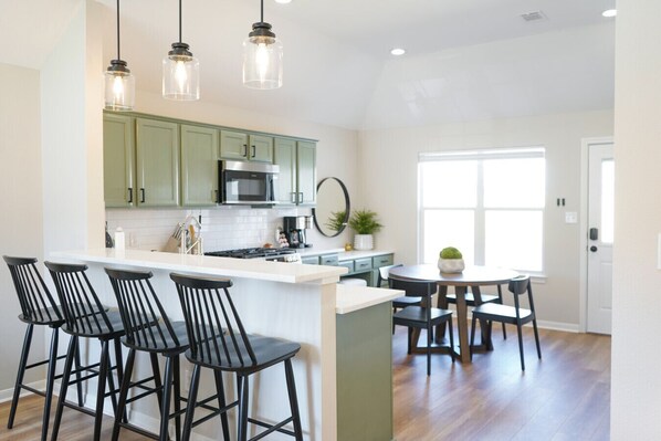 A modern kitchen with a central island, bar stools, and pendant lighting.