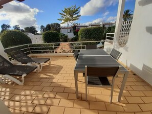 A patio with a table and chairs, a white railing, and a view of the surrounding area. - Villa Gaivota Ferragudo Terrace (Lagoa)